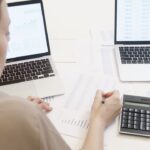 To personer analyserer nøgletal og grafer på bærbare computere